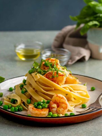 A plate of lemon fettuccine with garlic shrimp, garnished with parsley.