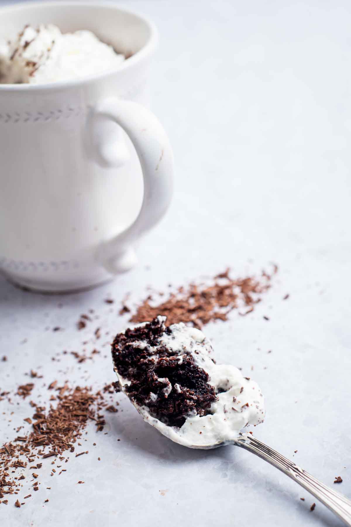 A spoonful of mocha mug cake and whipped cream, ready to be eaten!