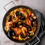 An overhead shot of a paellera filled with a beautiful seafood paella Valenciana.