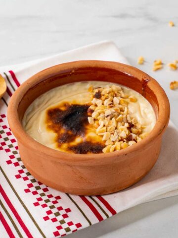 A clay pot of sutlac (baked Turkish rice pudding) decorated with hazelnuts.