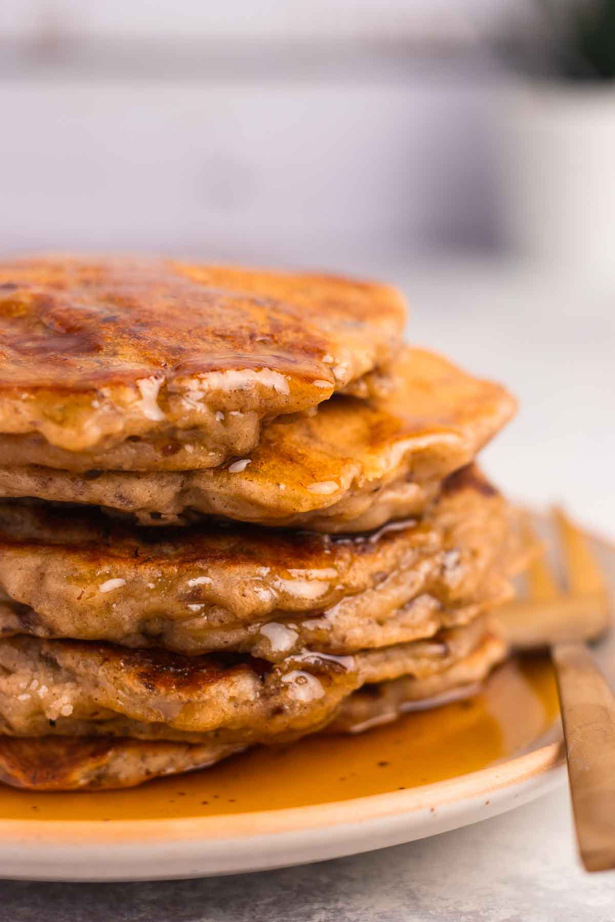 A close-up of banana pancakes with maple syrup poured over them.