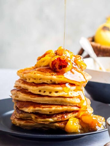 Maple syrup being poured on to a stack of buttermilk Pancakes with Caramelized Bananas