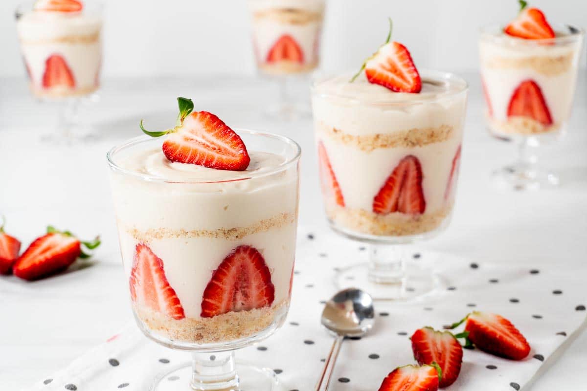 Several strawberry magnolia filled glasses. The layers of the dessert can be seen.