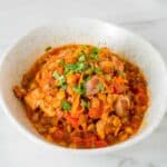 Harissa chicken with lentils in a white bowl.