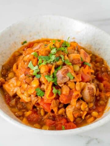 Harissa chicken with lentils in a white bowl.