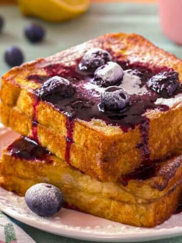A close-up of lemon blueberry French toast. The stuffed French toast is topped with blueberry compote, and powdered sugar.