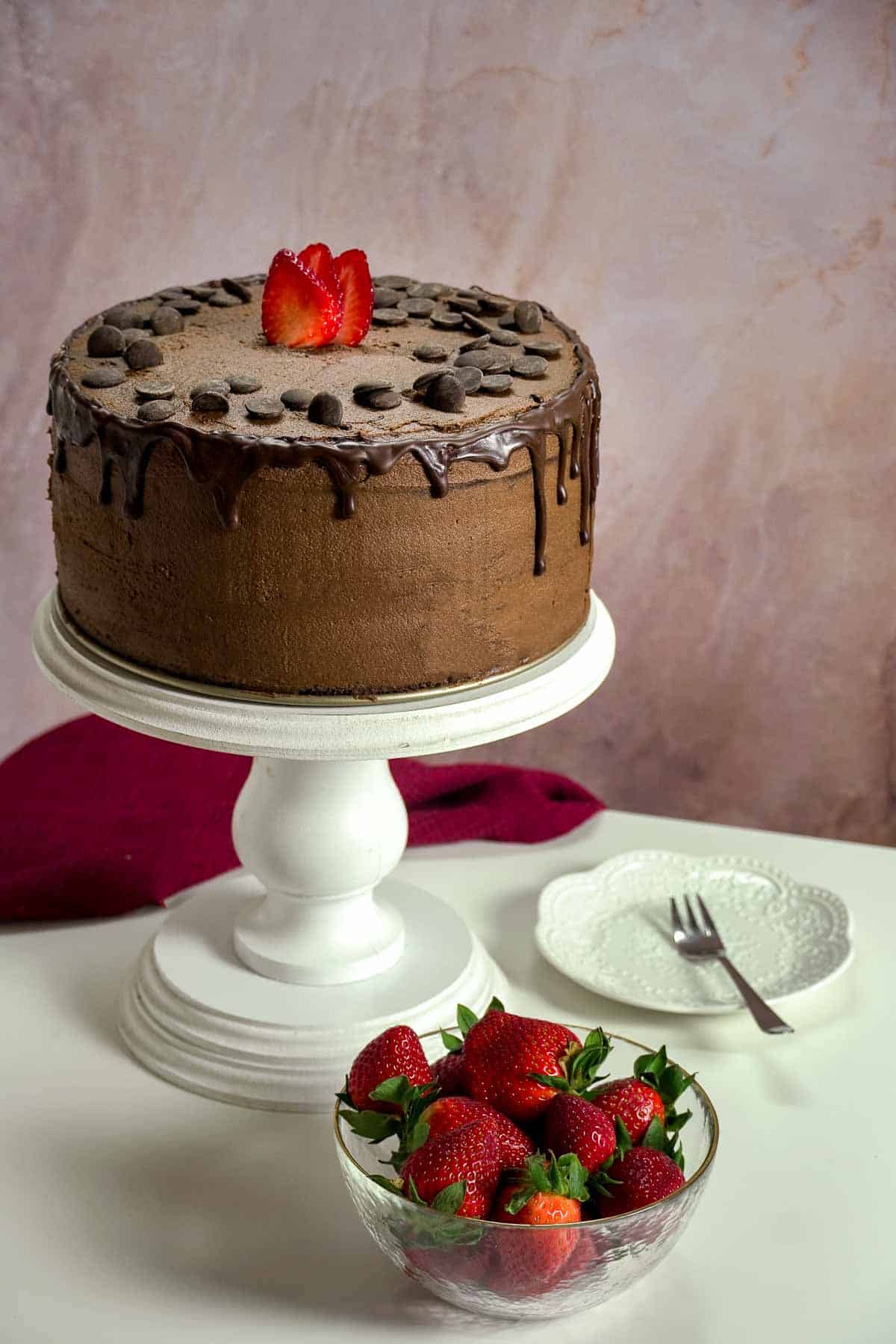 A chocolate cake with a bowl of strawberries next to it.