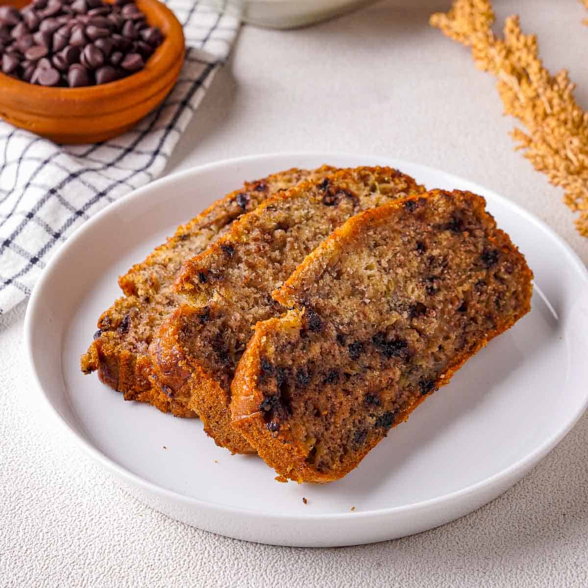 Three slices of chocolate chip banana bread on a white plate.