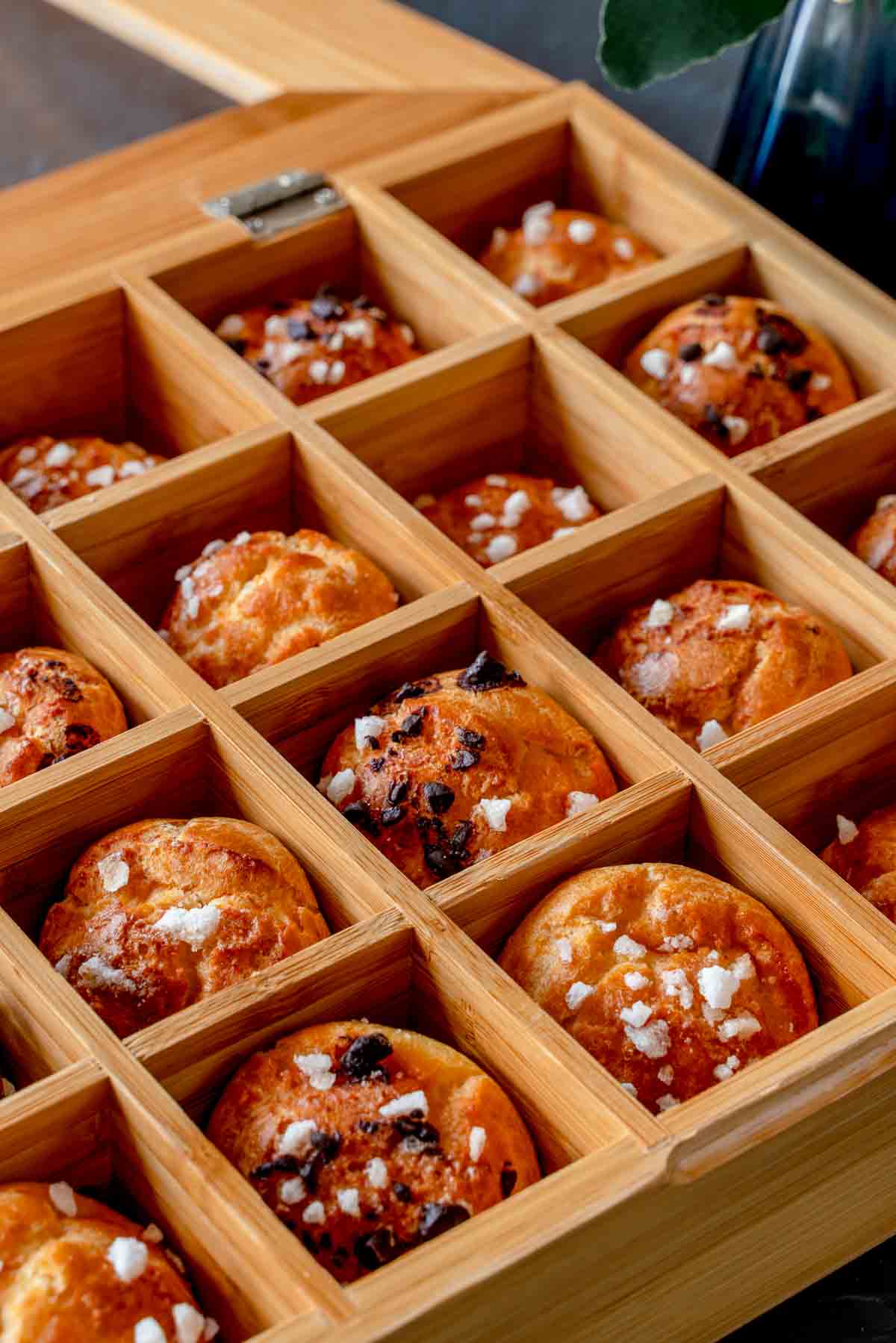 Chouquettes in a wooden box. Some have pearl sugar only, and others also have chocolate on them.