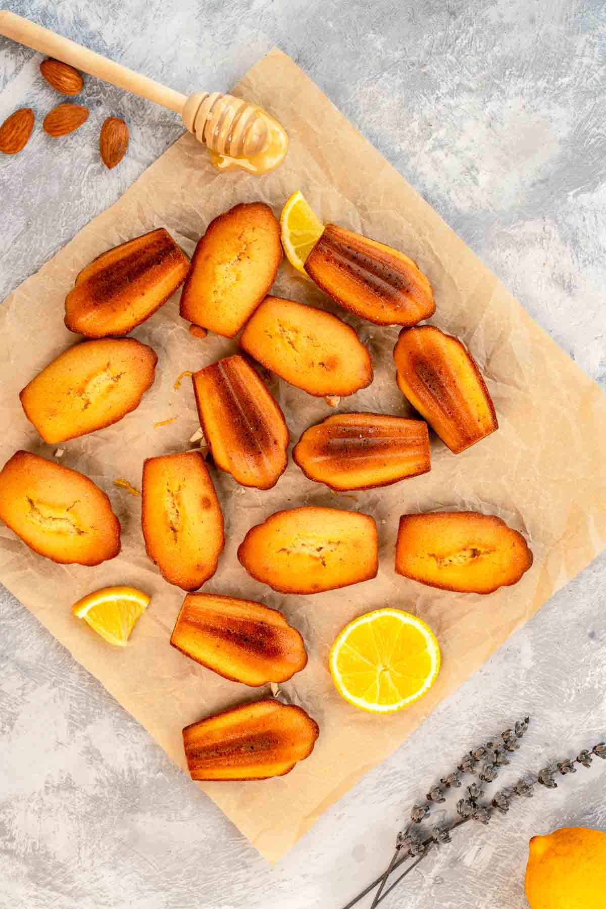 Madeleines on parchment paper with some honey next to them.