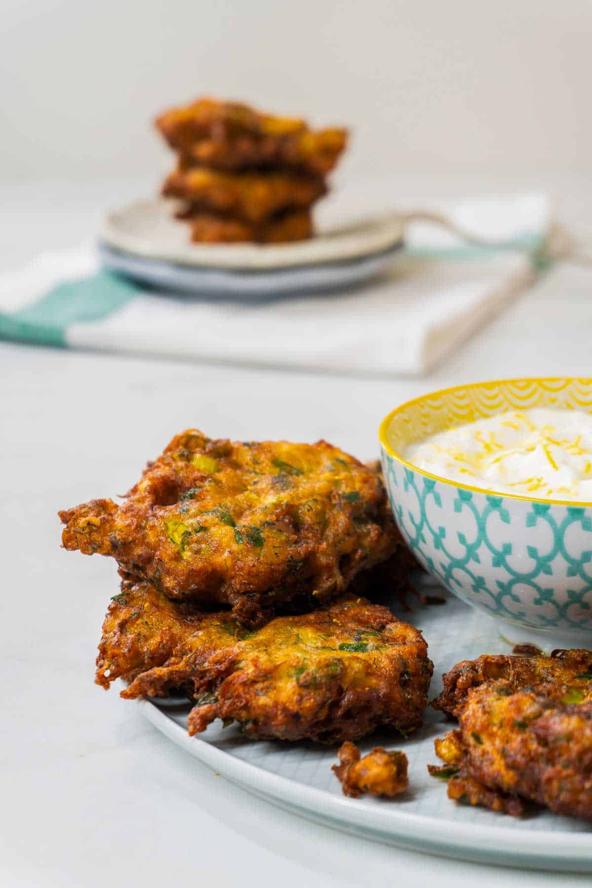 Turkish Courgette Fritters on a plate next to a bowl of yoghurt dip.