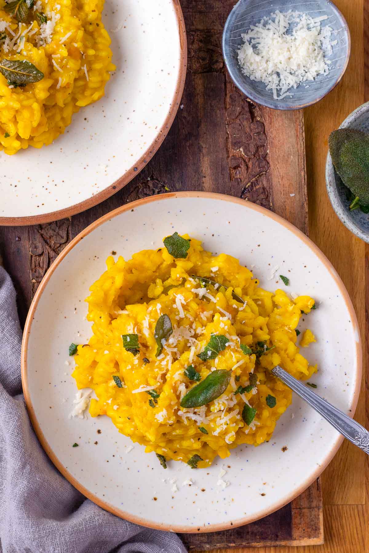 A top down shot of two plates of creamy pumpkin risotto.