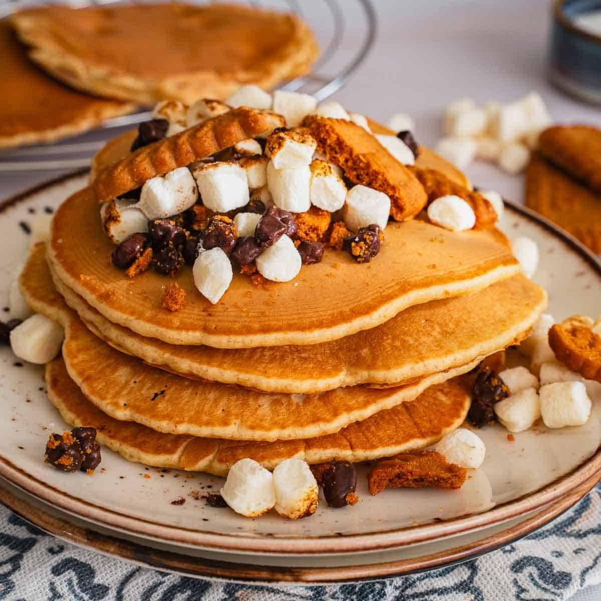 A stack of pancakes with s'mores and biscoff cookies.