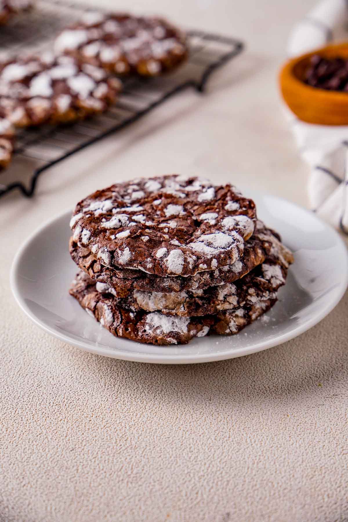Triple Chocolate Meringue cookies on a plate with more blurred cookies and chocolate chips in the background.