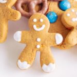 A smiling gingerbread man with white icing, carved from a gingerbread cookie.