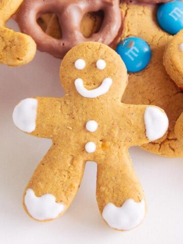 A smiling gingerbread man with white icing, carved from a gingerbread cookie.