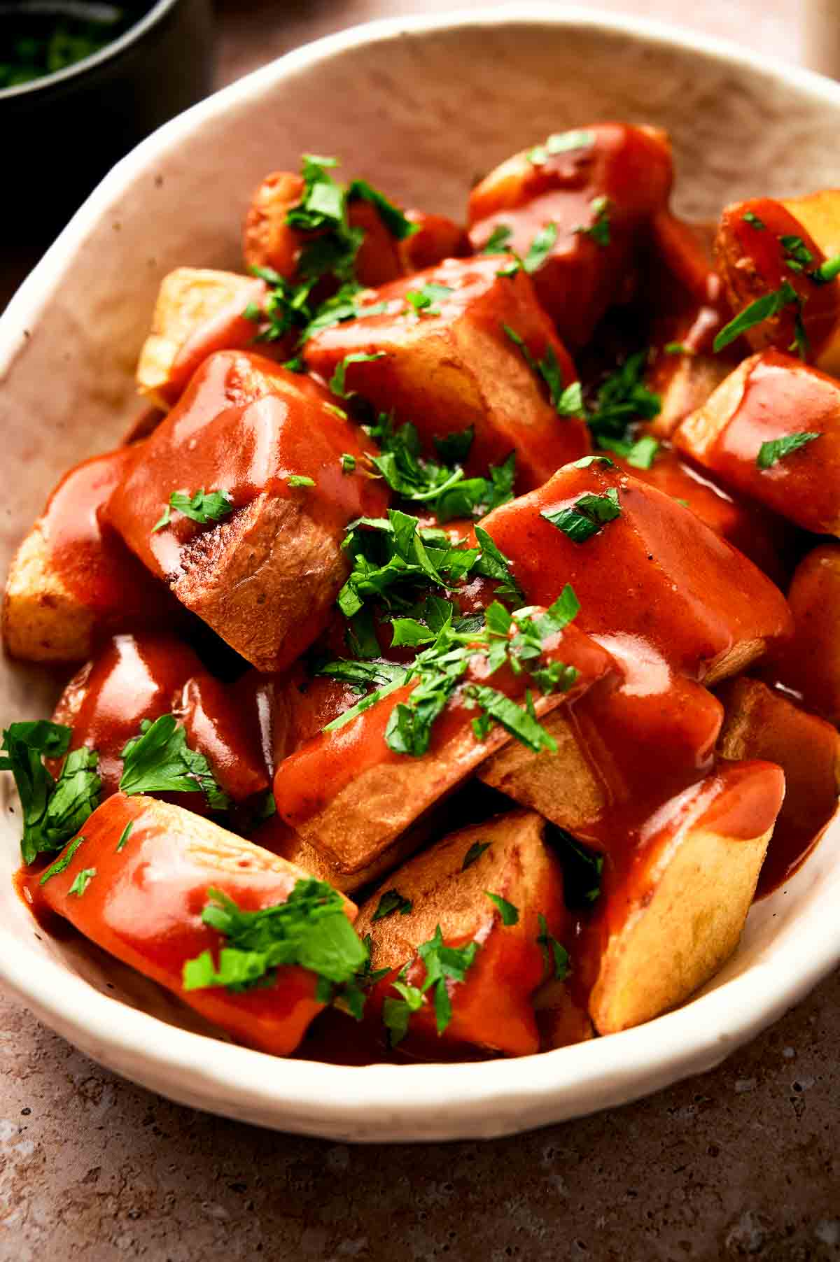A close-up of patatas bravas. The bravas salsa is red over the fried potatoes.