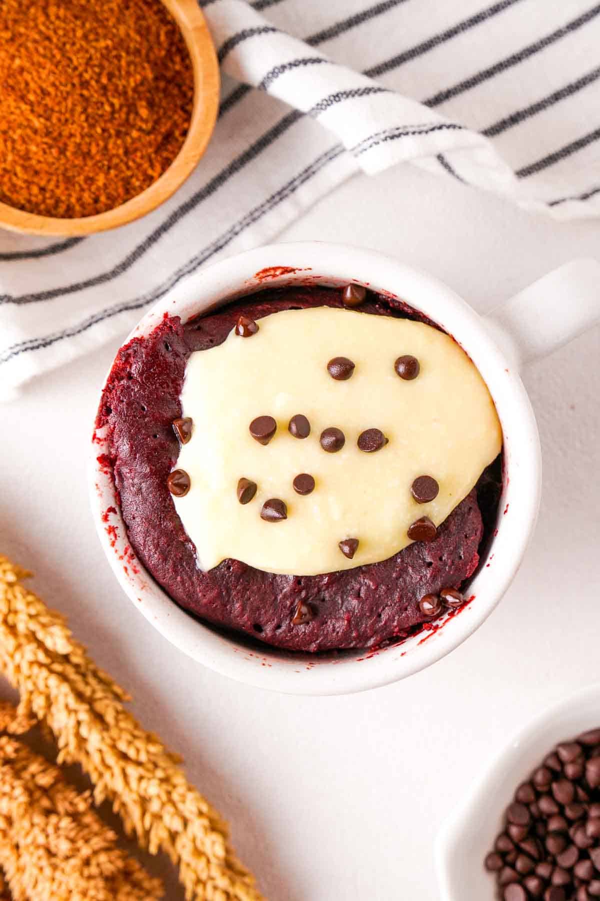 A top down view of red velvet mug cake that shows the cream cheese frosting with mini chocolate chips.