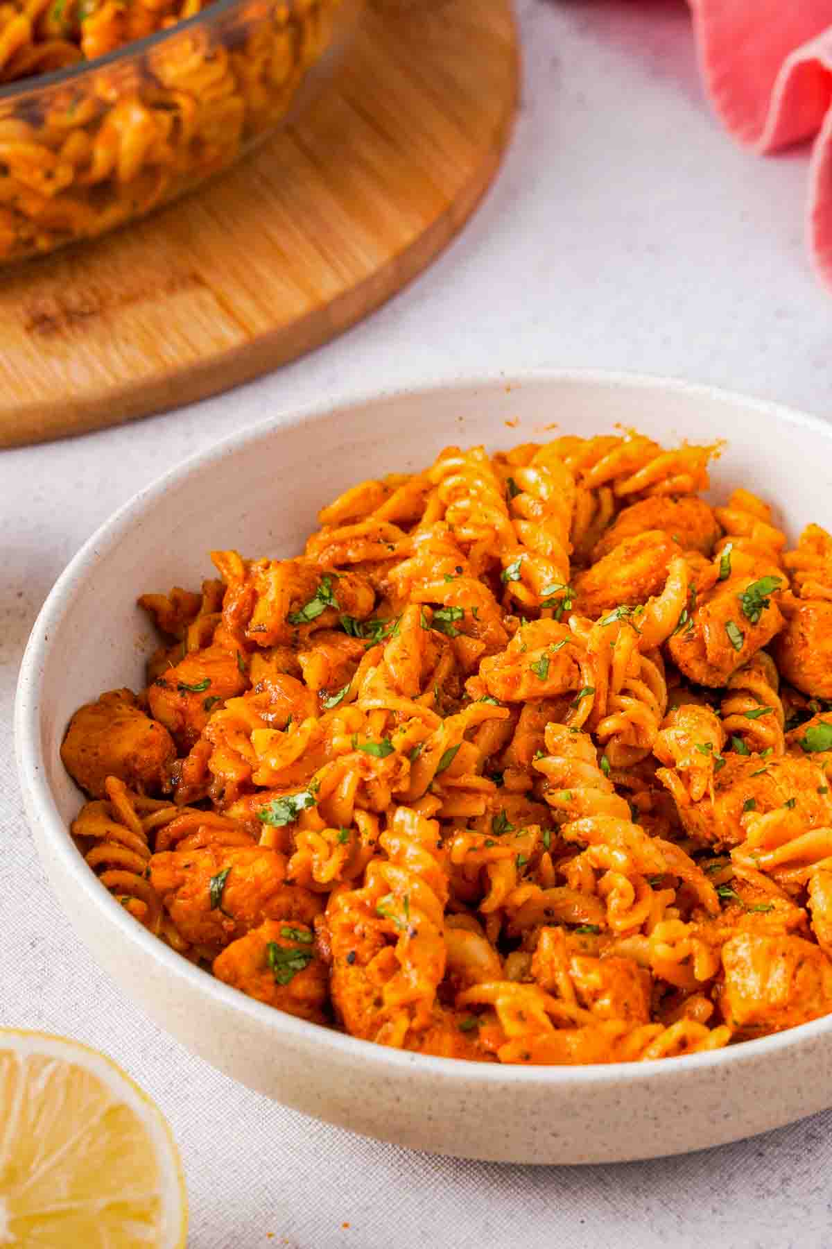 A bowl of butter chicken curry mixed with fusilli pasta.