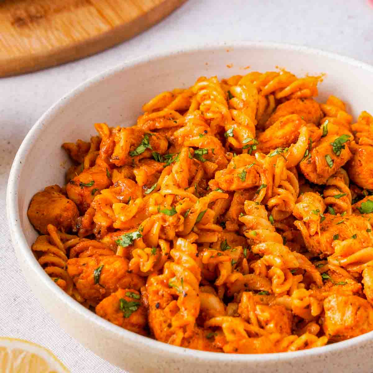 A white bowl of butter chicken pasta.