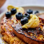 A dollop of mascarpone with blueberries and lemon zest on mascarpone French toast.