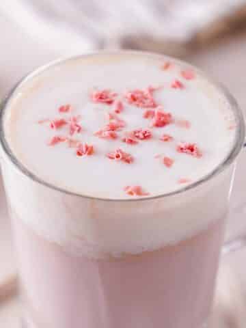 A close-up of ruby hot chocolate with ruby chocolate shavings atop lightly whipped cream.
