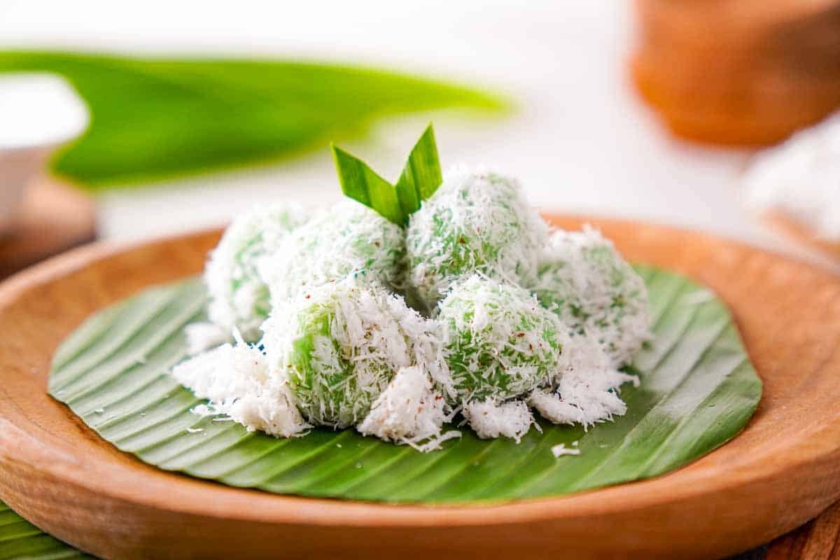 A close-up of onde onde covered in a generous amount of grated coconut.