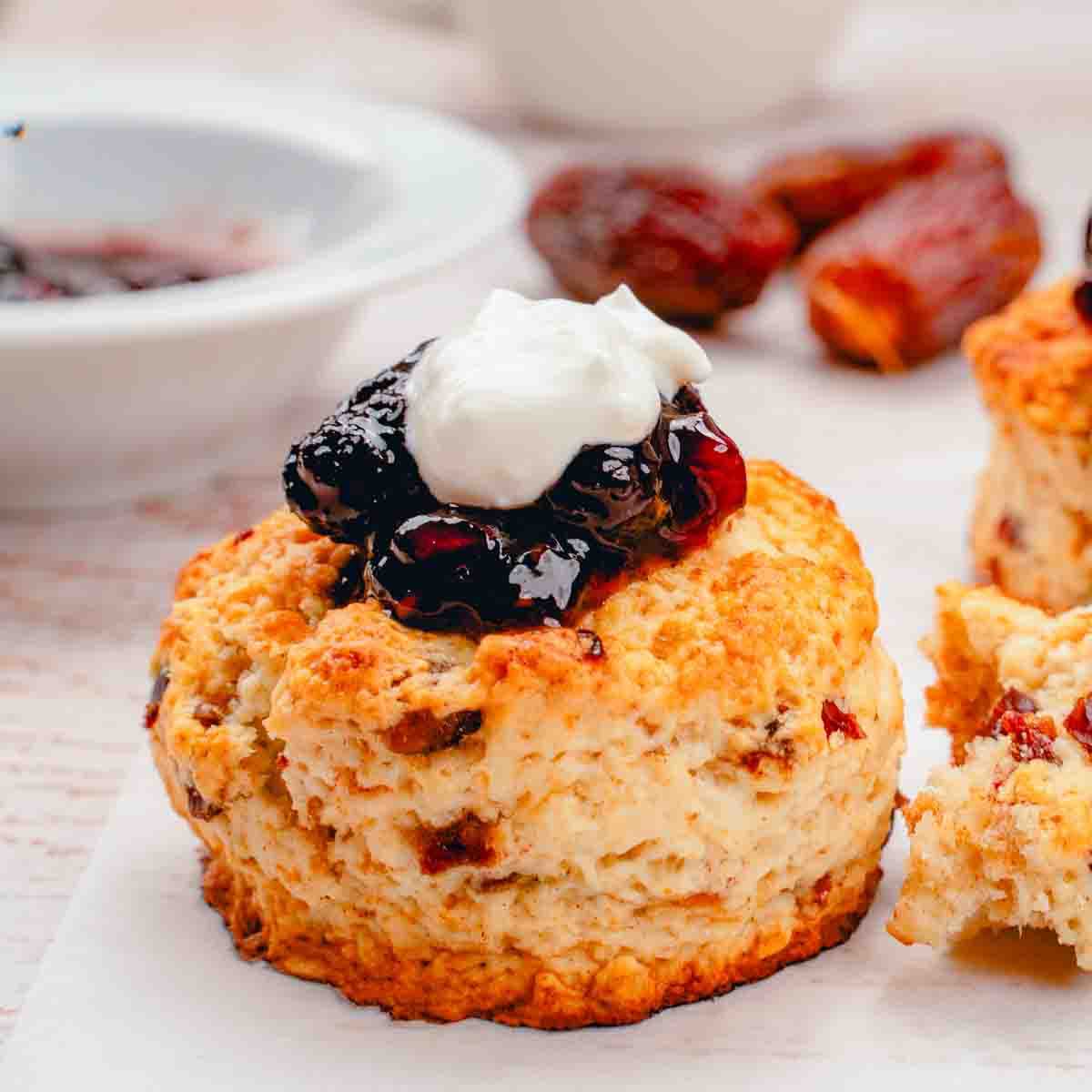 A date scone topped with jam and cream.