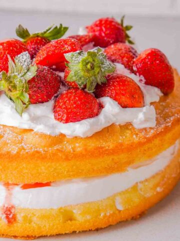 A Victoria Sponge Cake with Balsamic Strawberries. The cake has been delicately topped with icing sugar.