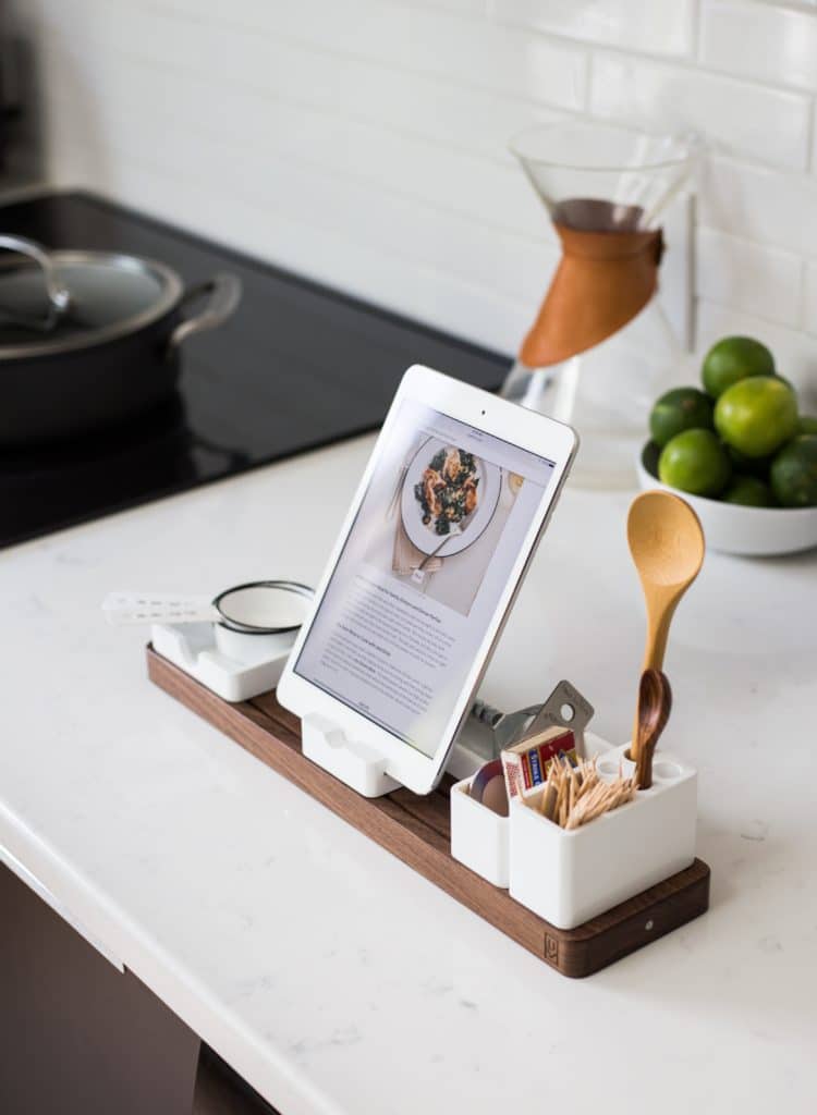 A ¾ quarter view of an iPad with a recipe on it, on a stand that also include cooking utensils.