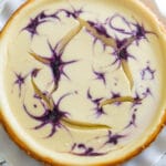 A bright overhead photo of a creamy Blueberry Swirl Cheesecake with a few cracks in it.